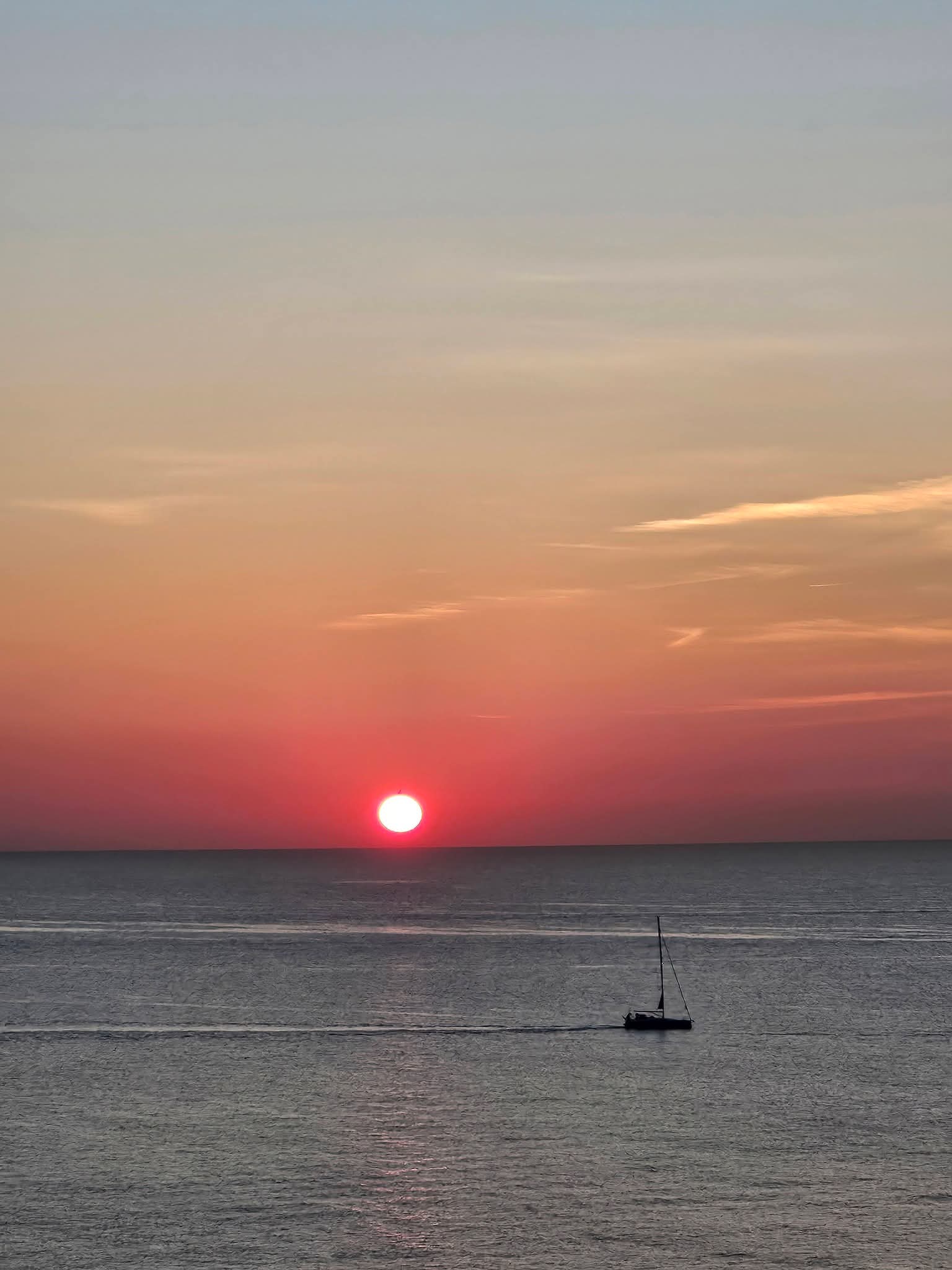 Sunset over water with sailboat